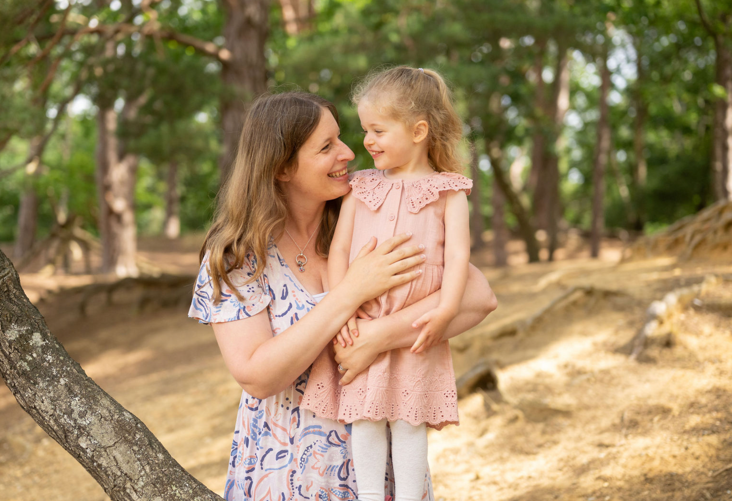 Woman and young girl hugging in a forest setting
