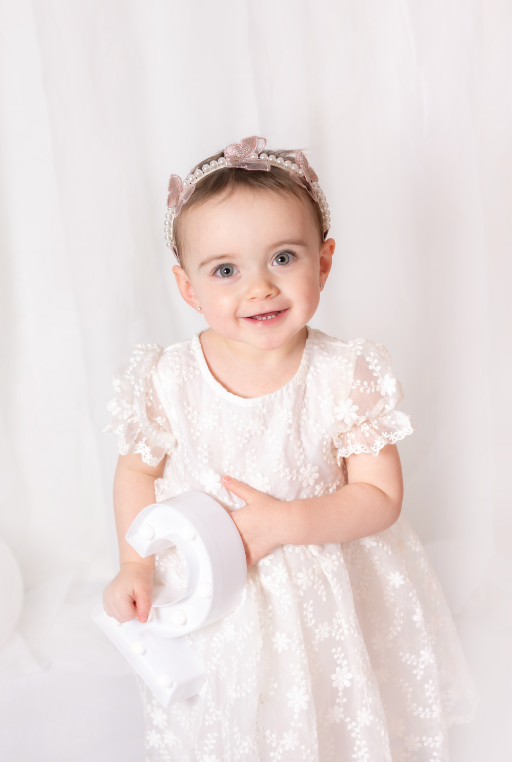 Child in a white dress with a tiara on a white background