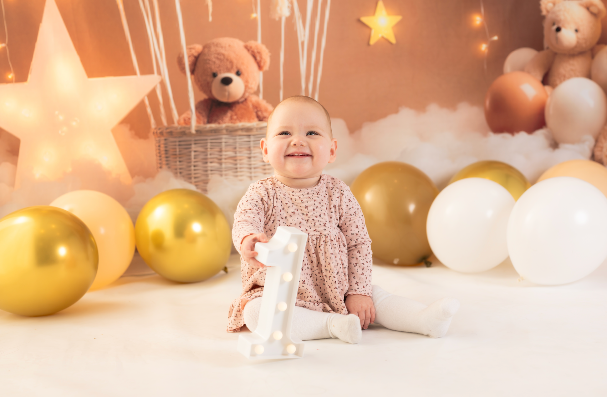 Baby sitting among balloons and teddy bears in a decorated room
