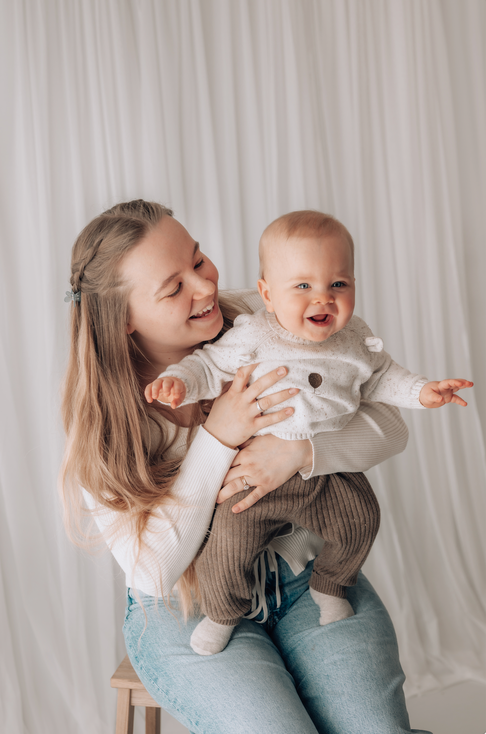 Woman holding a baby against a plain background during a family photoshoot in Surrey 