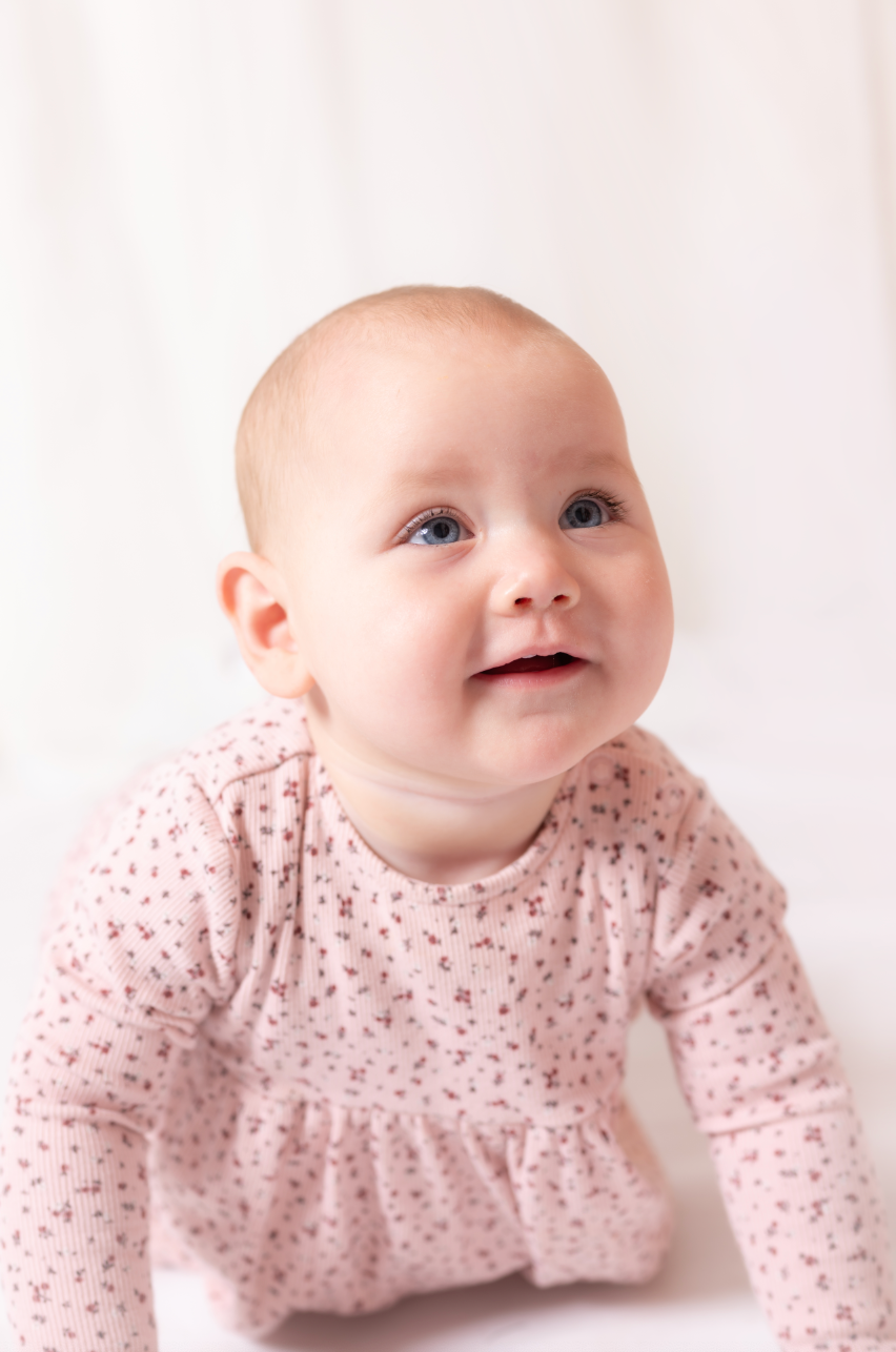 Baby wearing a pink floral outfit against a white background
