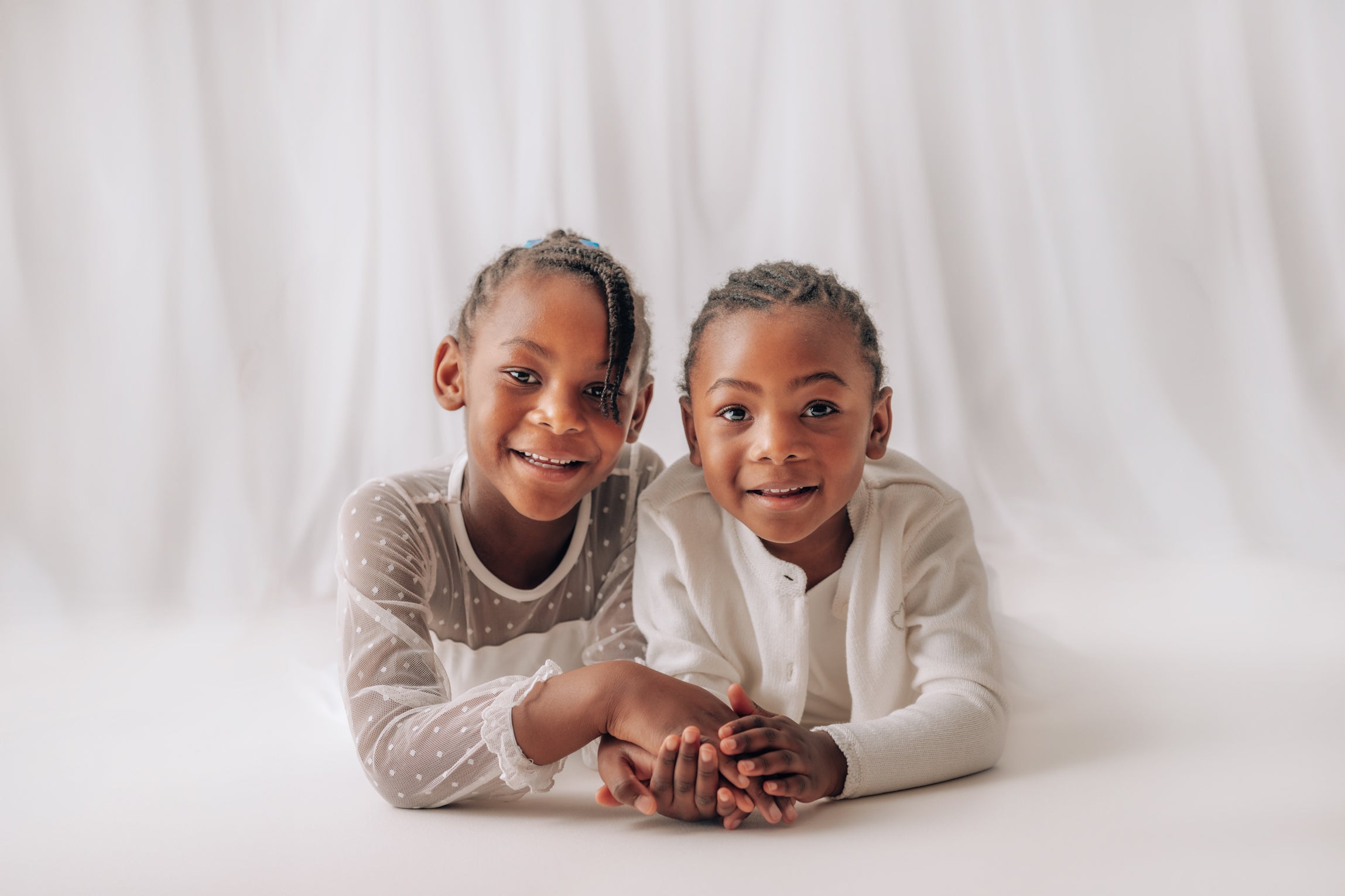 Two young girls sitting together on a white background