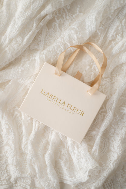 Beige gift bag with 'Isabella Fleur' branding on a textured white fabric background