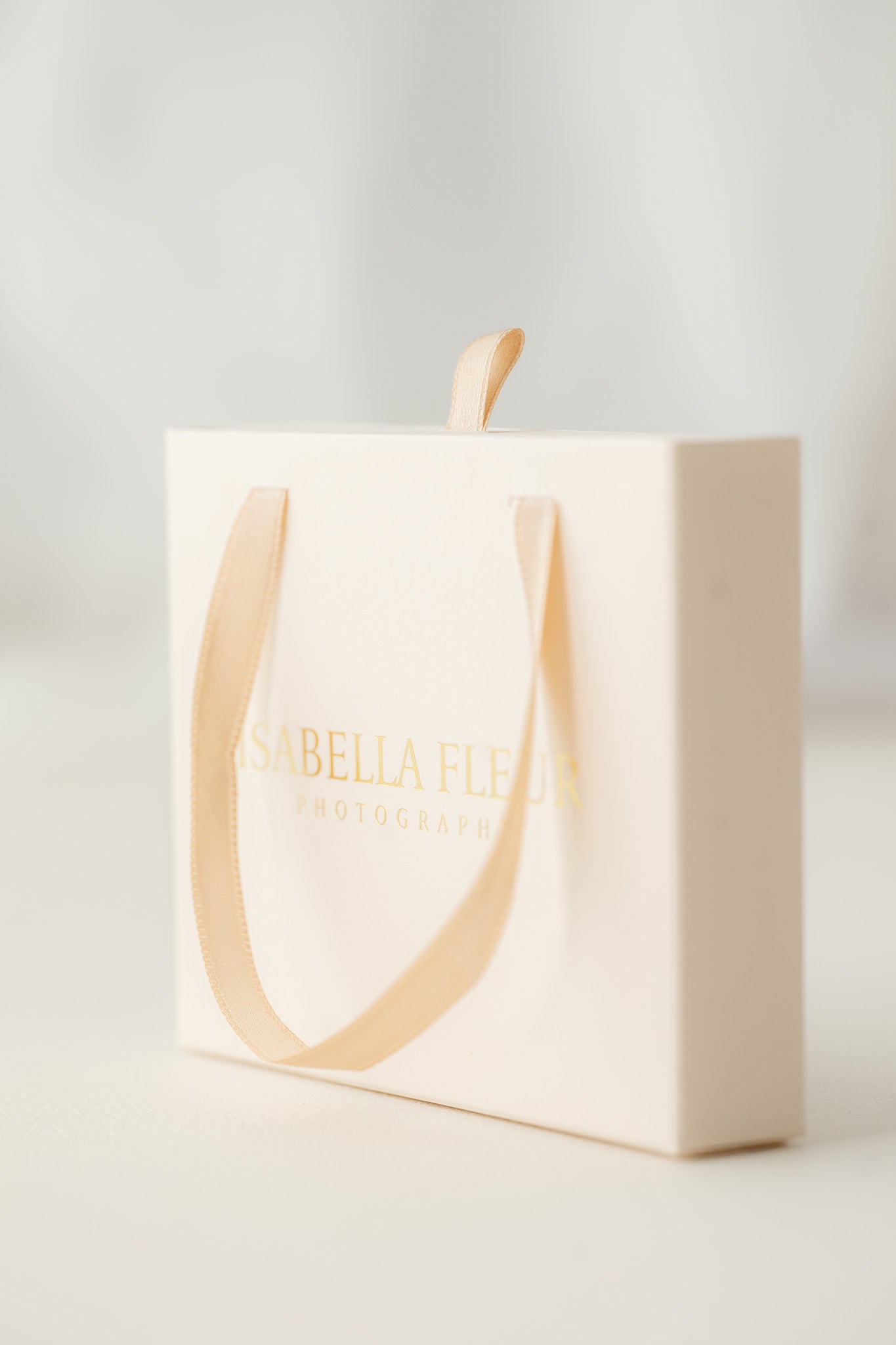 White gift box with gold handle and 'Isabella Fleur' branding on a light gray background