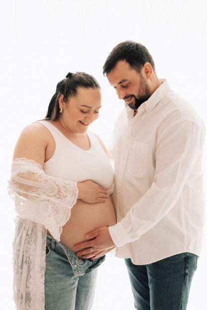 Pregnant woman with a man holding her belly against a white background