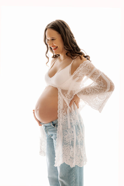 Pregnant woman wearing a white lace robe on a white background